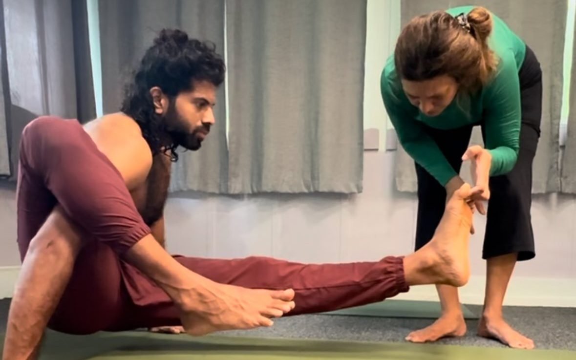 Christina giving a careful hands-on adjustment to a student at the shala